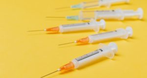 Pfizer and AstraZeneca Vaccines Yellow Background Syringes